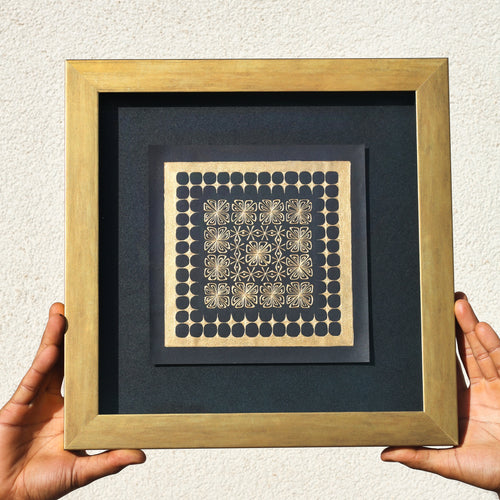 Framed artwork with geometric pattern held by hands against a neutral background